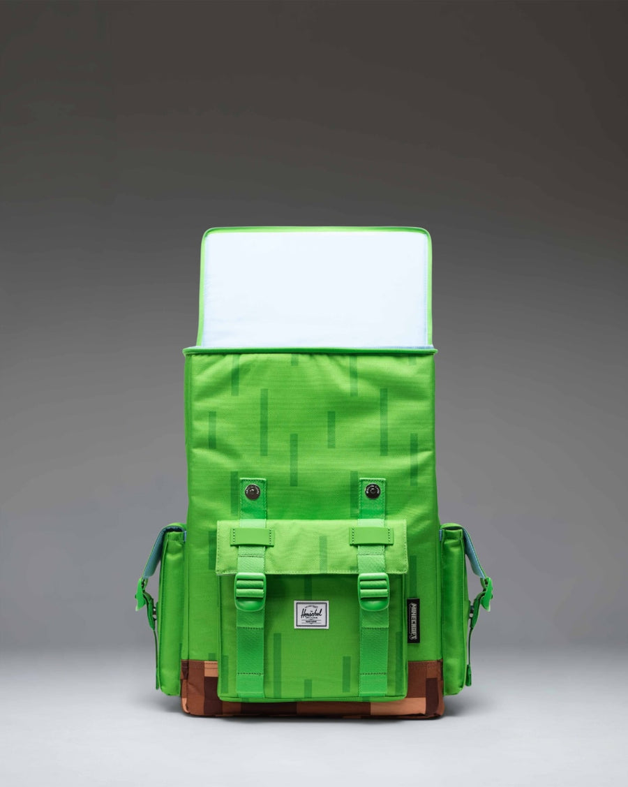 Minecraft Herschel Little America Cube Backpack in Grass Block color featuring a pixelated green and brown design with black straps.