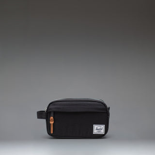 Herschel Supply Co Chapter Small Travel Kit in black, showing the compact toiletry bag with its side handle and classic woven label.
