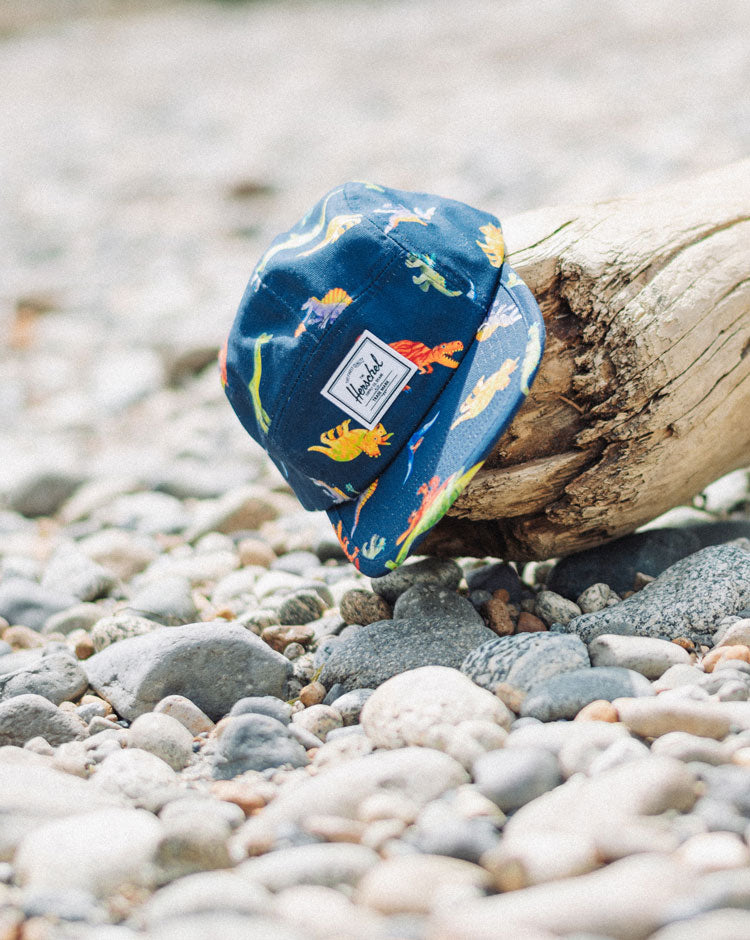 Herschel Supply Co. Glendale Kids Cap in Water Colour Dinosaurs Darkest Navy, featuring a colorful dinosaur pattern on a dark navy blue base.